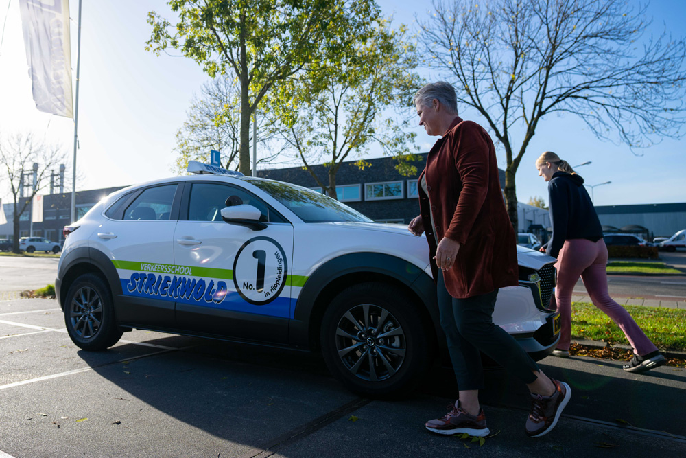 Leerling en instructeur lopen naar de lesauto van Verkeersschool Striekwold